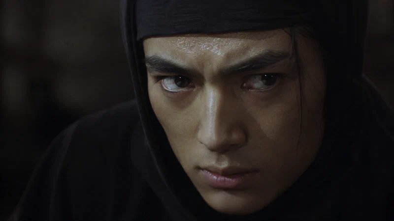 ภาพโคลสอัพแววตาที่เต็มไปด้วยความกดดันและความมุ่งมั่นภายใต้หน้ากากนินจา สะท้อนวิกฤตตัวตน